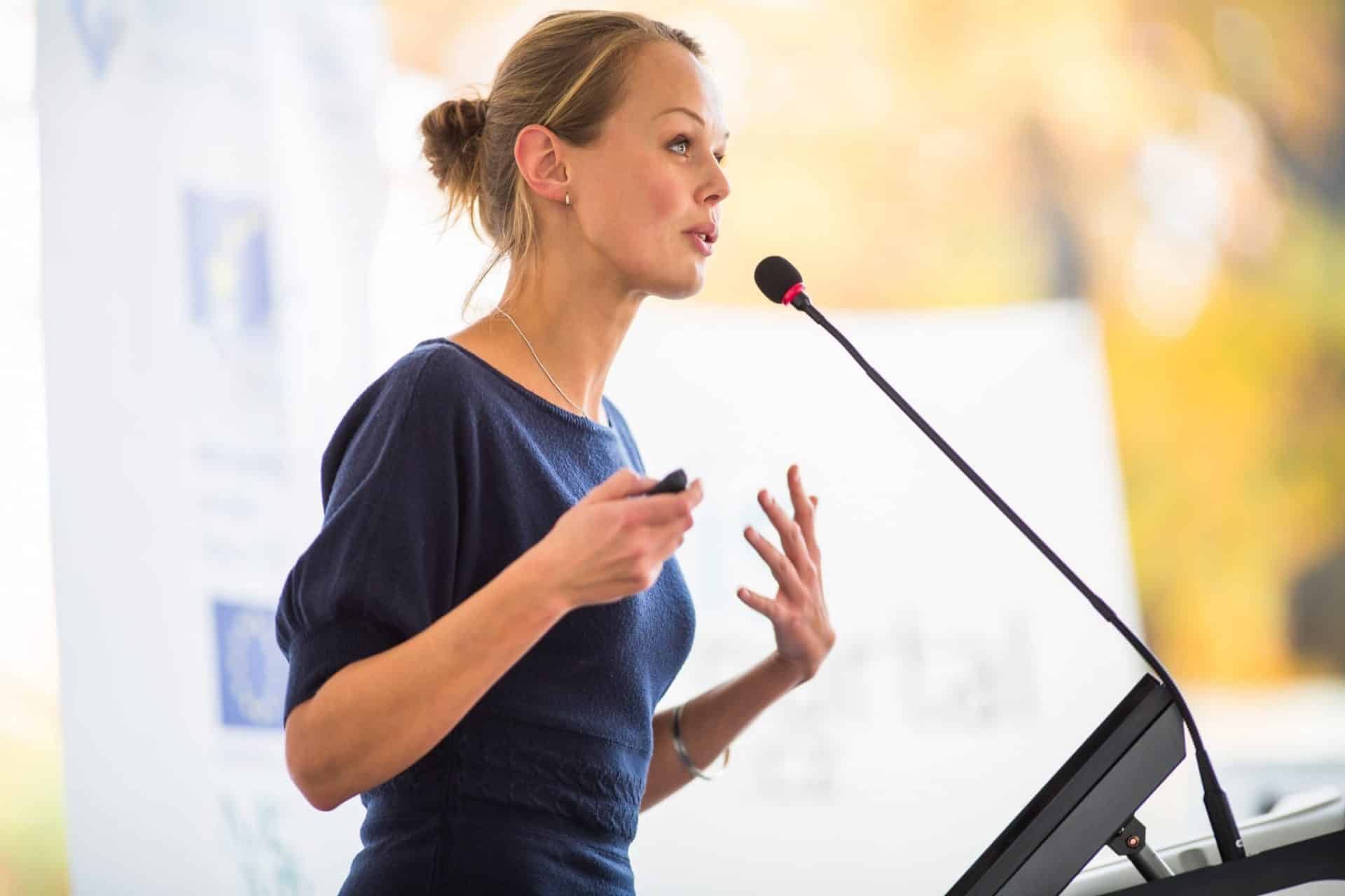 Modified Description: A woman engaging the audience with presentation techniques at a podium.