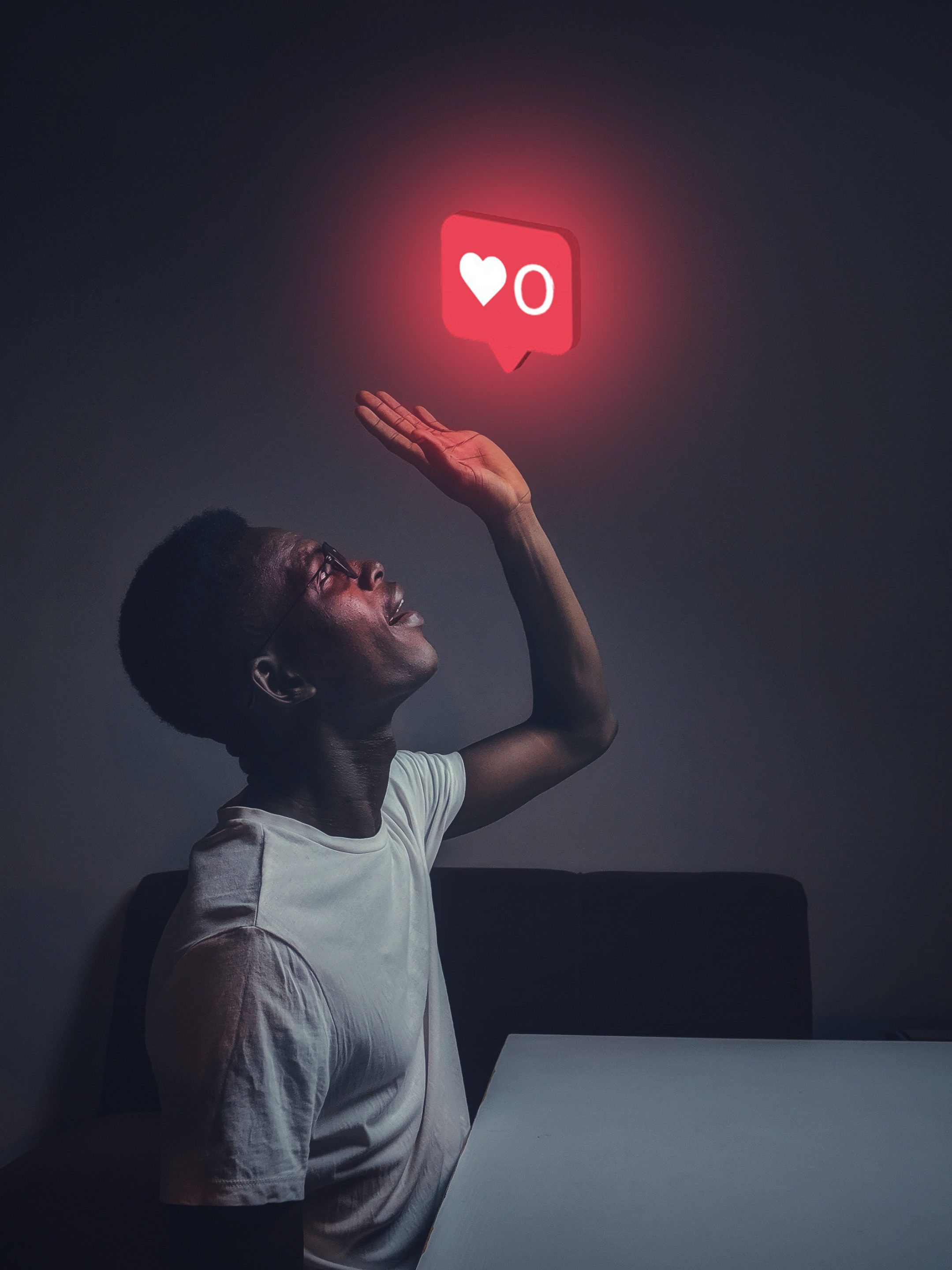 An influencer is holding up a red heart symbol in front of him.