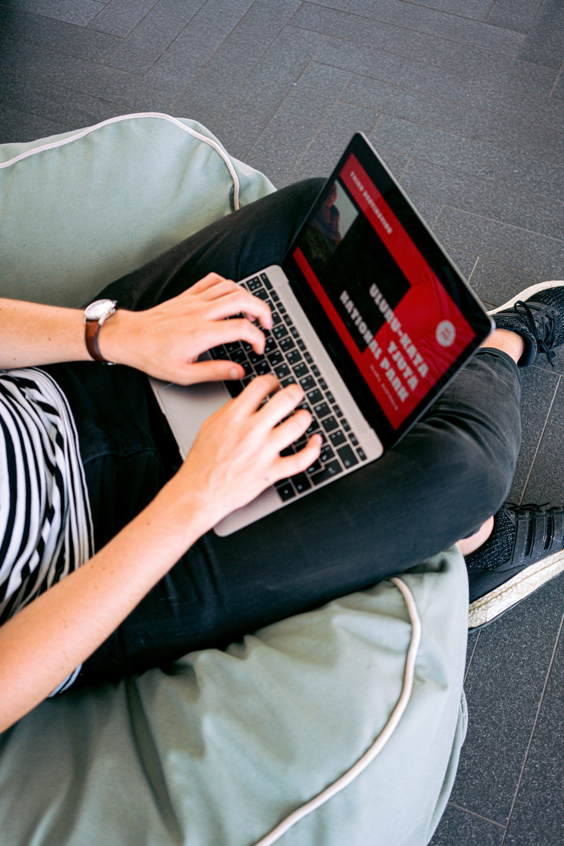 A woman comfortably using a laptop on a bean bag chair while interacting with user-friendly websites.