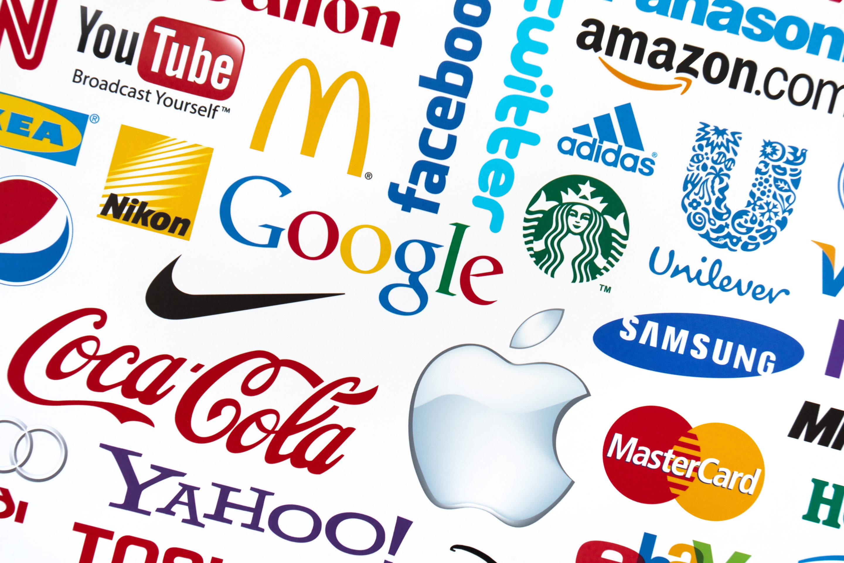 A collage of various company logos, including Apple, Google, Coca-Cola, Nike, Amazon, Twitter, Facebook, Samsung, Yahoo!, McDonald's, YouTube, Pepsi, Uber and MasterCard showcases the art of creating a memorable brand name while navigating copyright infringement.