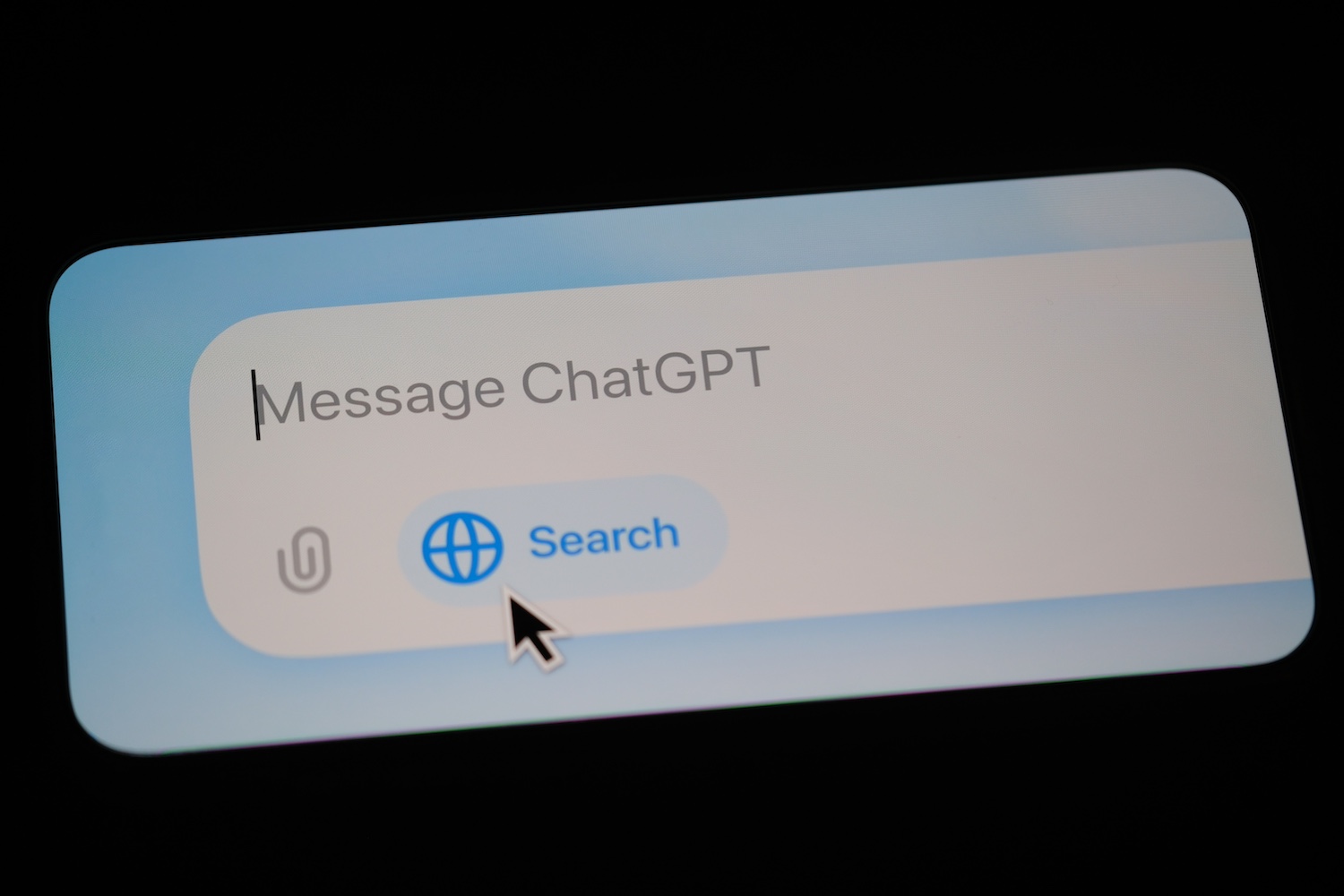 A screen displays the text “Message ChatGPT” alongside a paperclip icon for attachments and a globe icon labeled “Search,” with a cursor highlighting it, as AIO services enhance user interaction.