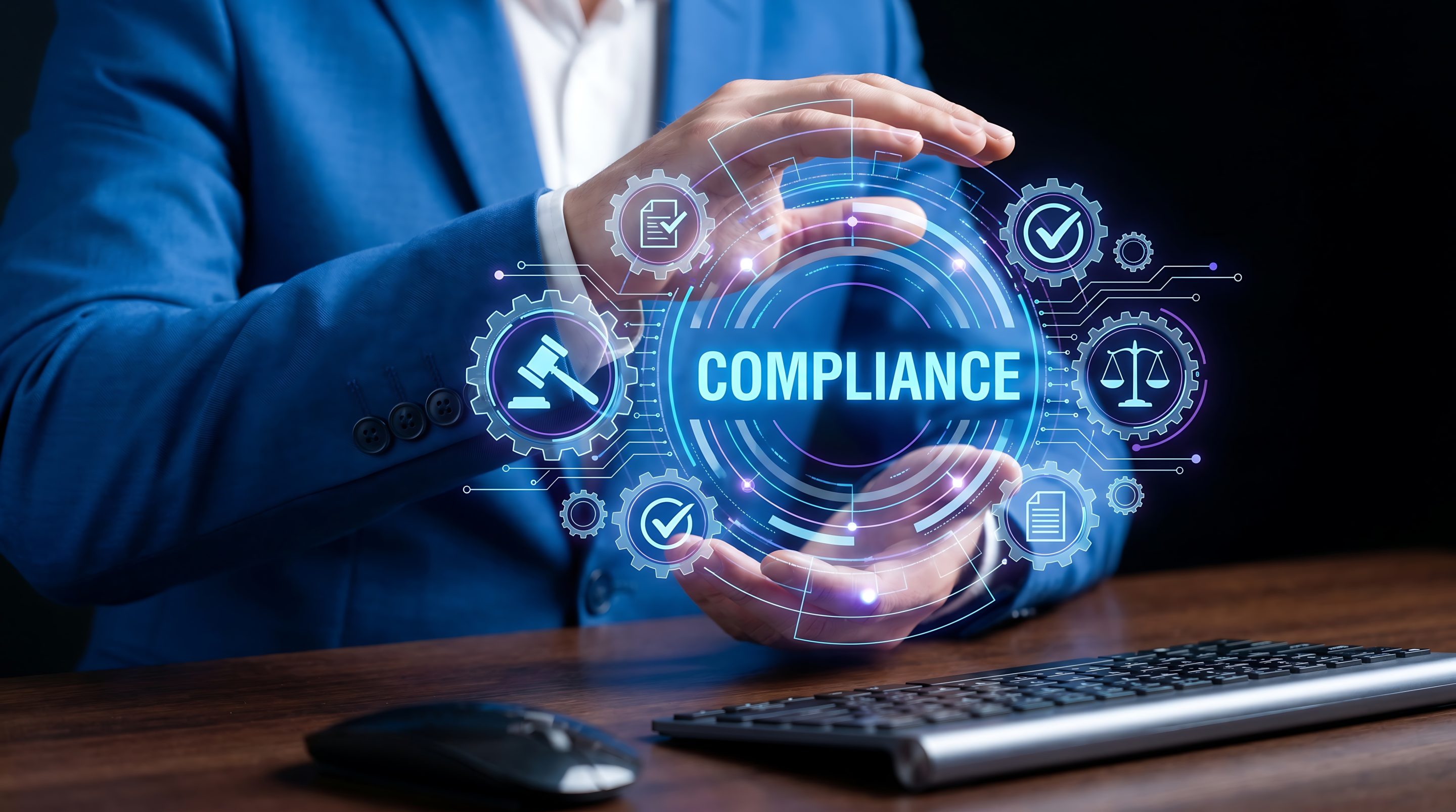 A person in a blue suit sits at a desk with a keyboard, holding their hands around a digital hologram that displays the word "COMPLIANCE" and various legal and regulatory icons. A person in a blue suit sits at a desk with a keyboard, holding their hands around a digital hologram that displays the word "COMPLIANCE" and various legal and regulatory icons.